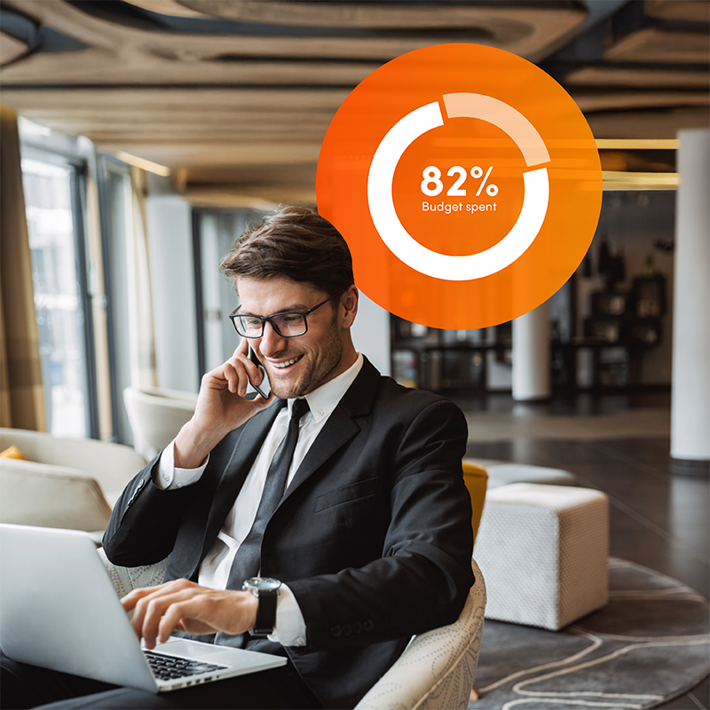 Businessman smiling at laptop with budget spend graphic, showing Elevate workforce management program ensures budget confidence for hospitality.