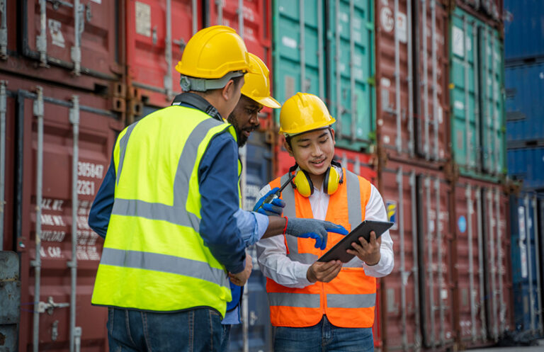 Maritime and port team members reviewing Elevate labour management system on a tablet, simplifying shift cover in high-volume operations.