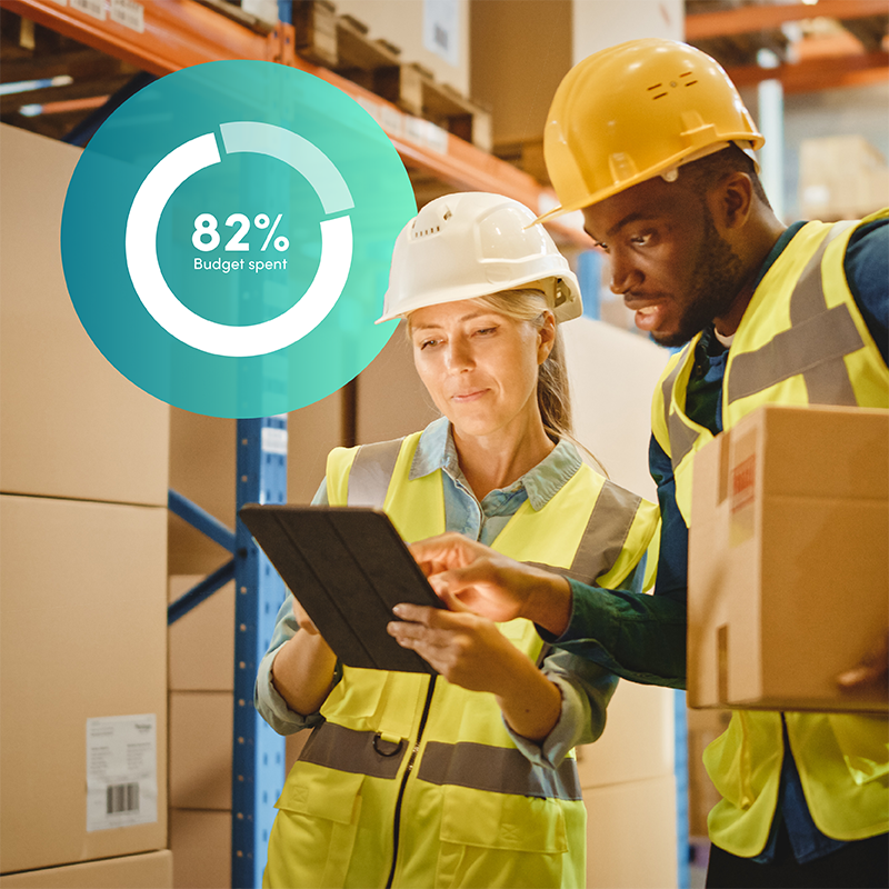Two warehouse workers in high-vis looking at tablet with budget spend graphic, showing Elevate workforce management ensures budget confidence for logistics.
